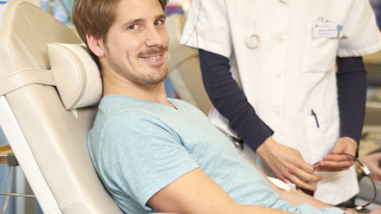 Junger Mann liegt auf einer Liege und spendet Blut
