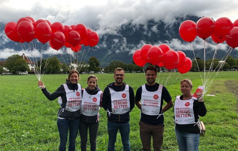 Junge Menschen stehen draußen mit Luftballons und machen auf eine Blutspendeaktion aufmerksam