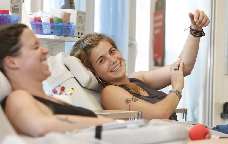 Das Bild zeigt zwei Frauen bei der Blutspende, die lachen.