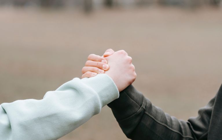 L'immagine mostra due mani che si stringono in segno di saluto. 